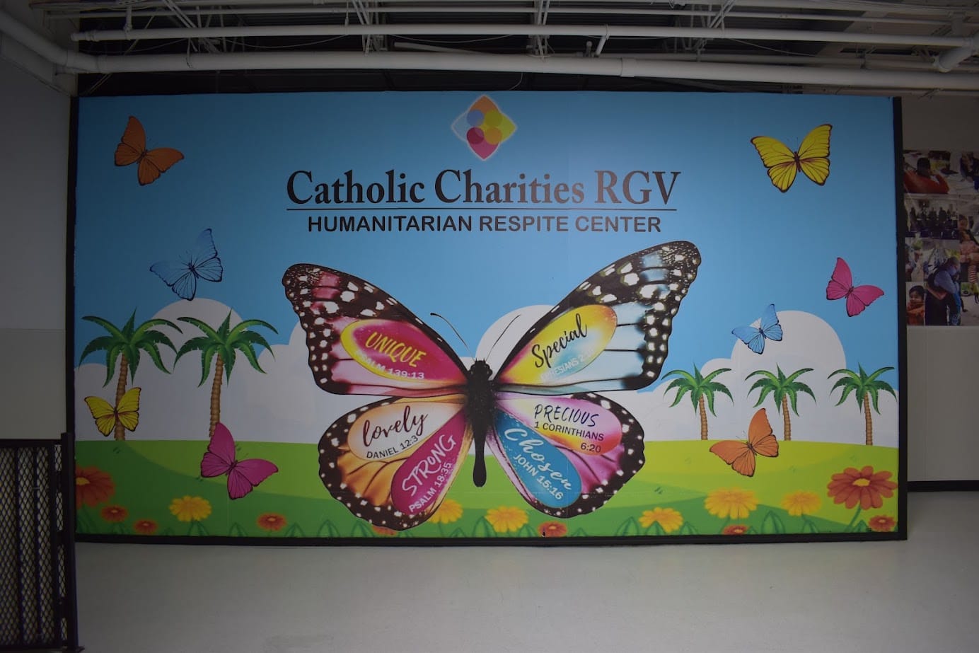 Colorful butterfly mural with Catholic Charities RGV Humanitarian Respite Center lettering.