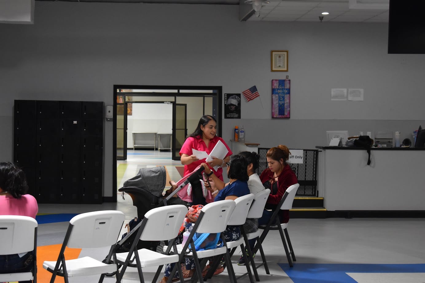 An adult standing beside a seated classroom discussion group.
