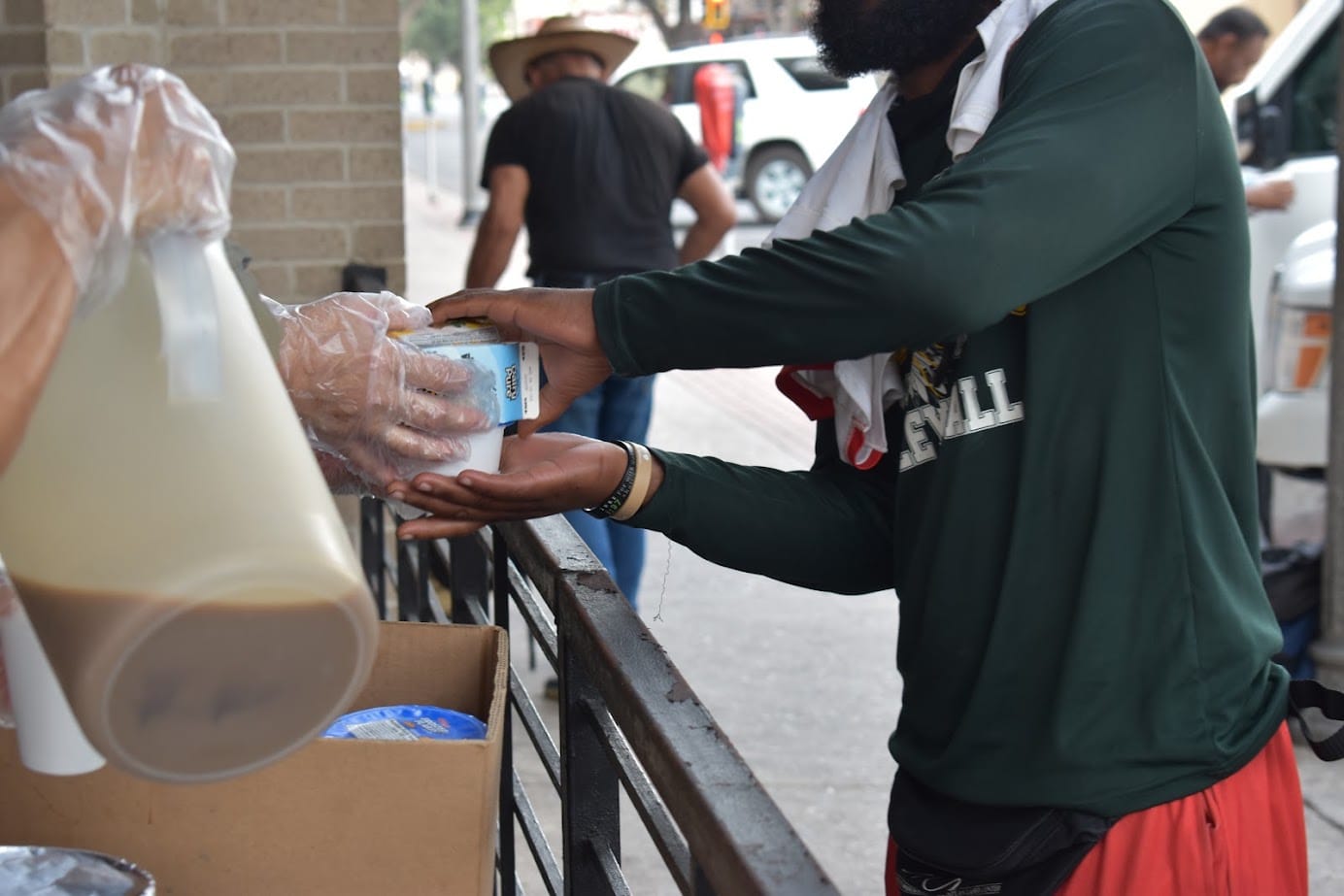 A cup being handed across the Catholic Charities RGV meal-service counter