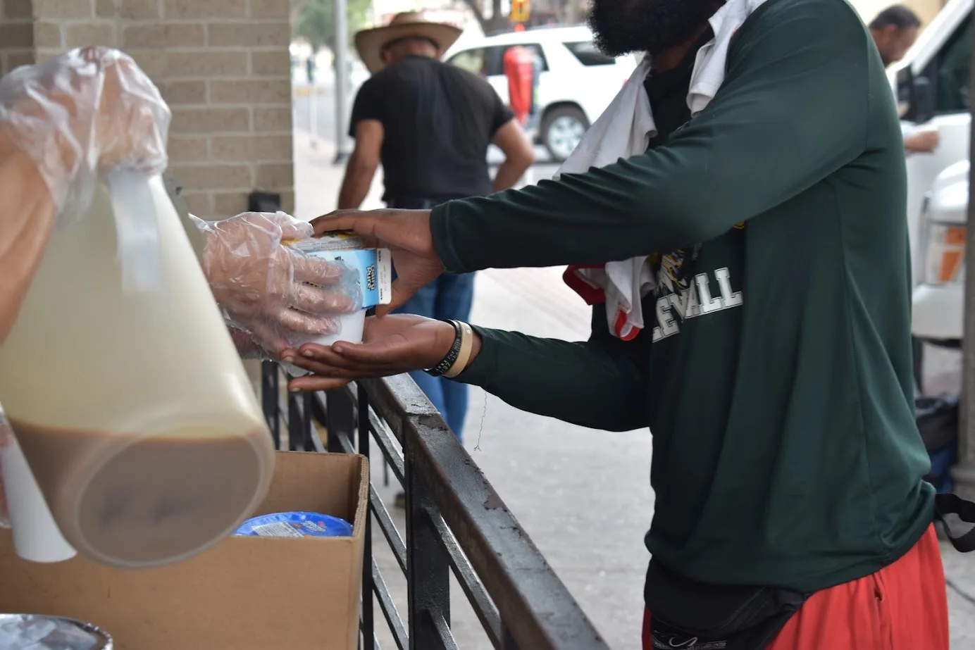 A cup being handed across the Catholic Charities RGV meal-service counter