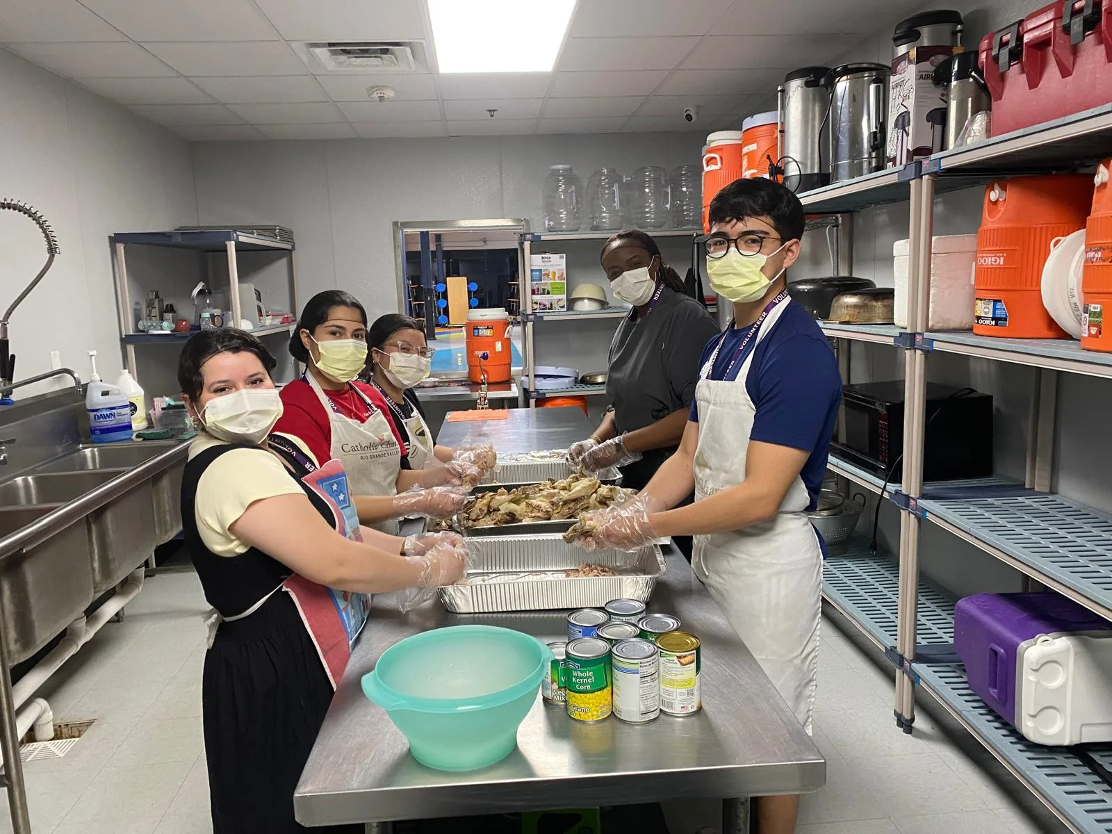 People in aprons preparing food in a kitchen.
