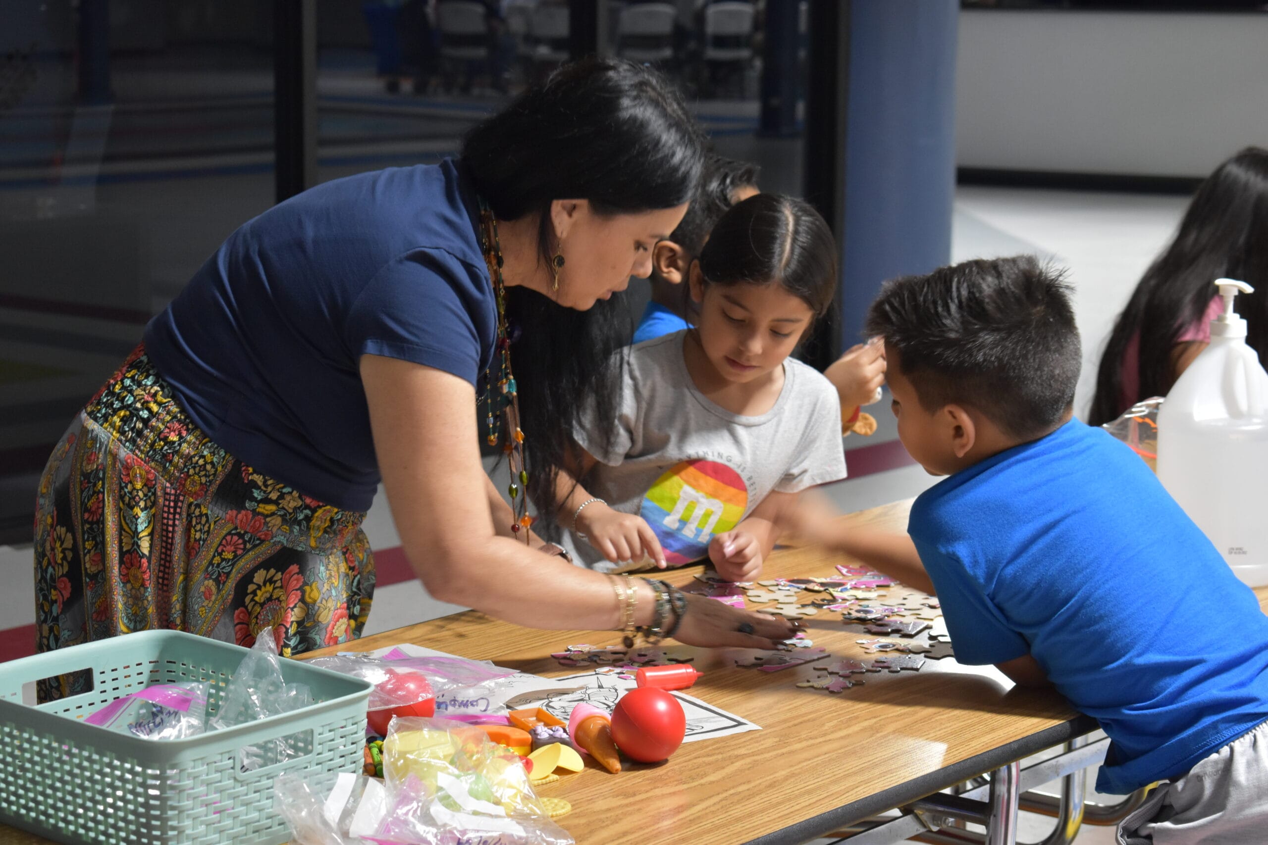 An adult and children working on a puzzle at a table.