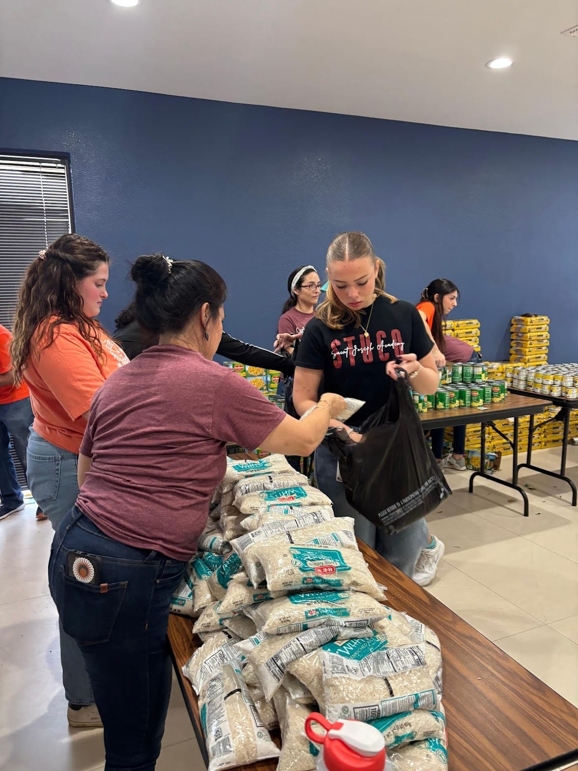 Volunteers packing food bags with rice and canned goods at Sharing Basket.